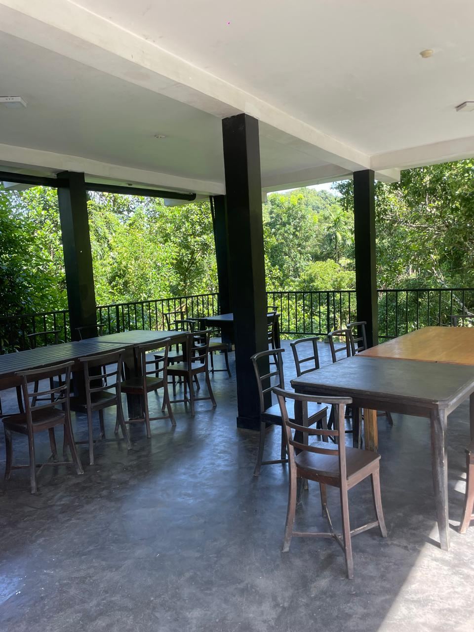 Open-air dining pavilion with tables looking out over the trees