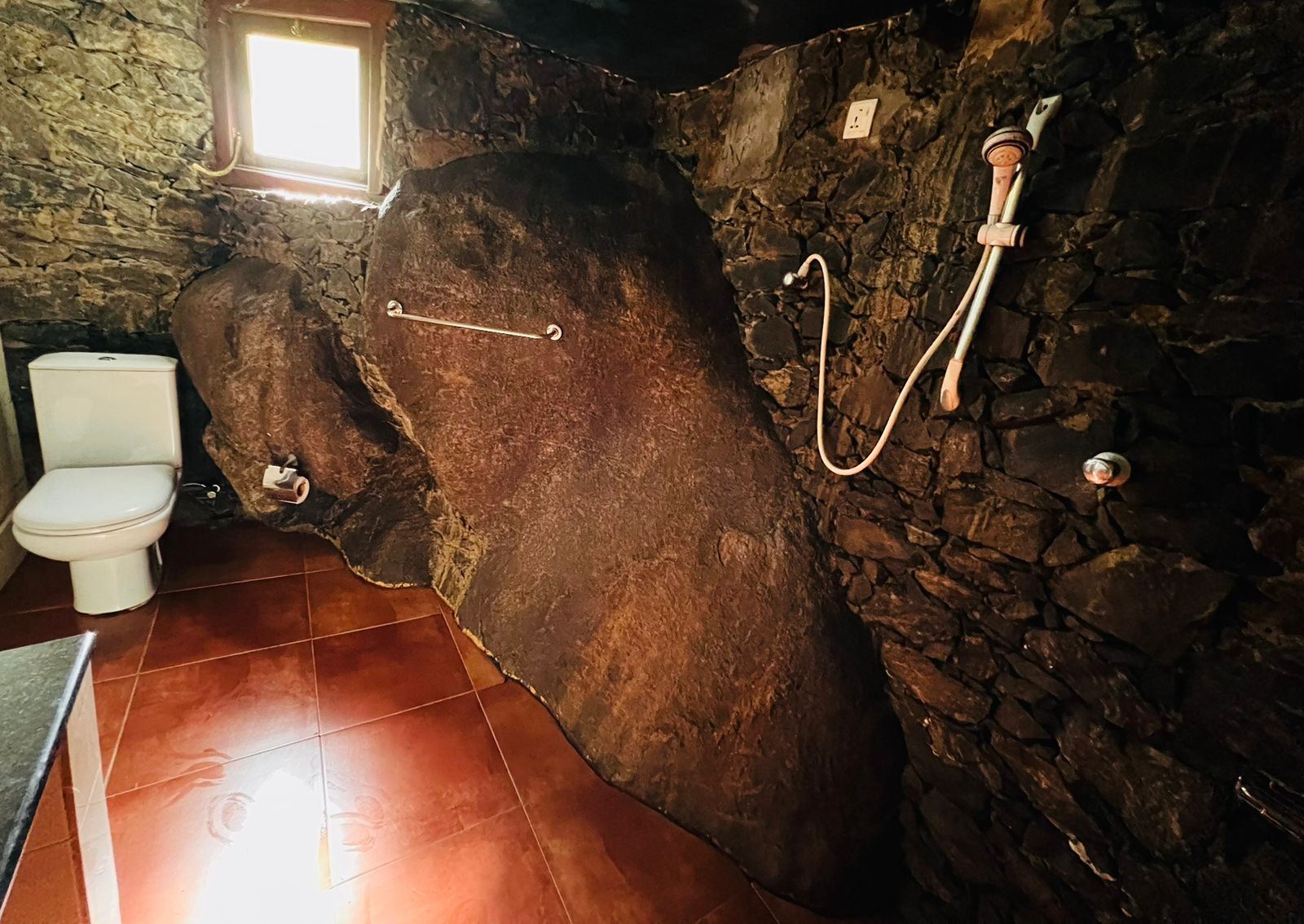 Bathroom shower set against a natural rock face